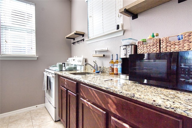 kitchen featuring light stone counters, electric stove, sink, and light tile patterned floors