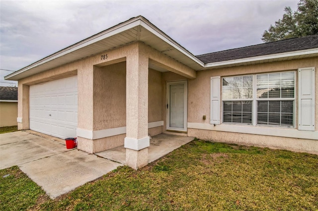 entrance to property featuring a garage and a lawn