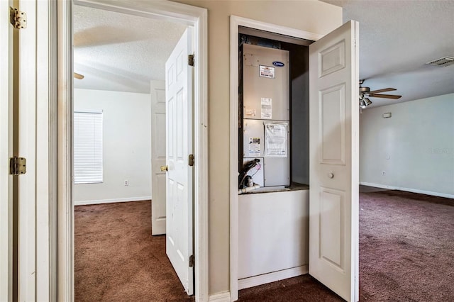 corridor with a textured ceiling, heating unit, and dark colored carpet