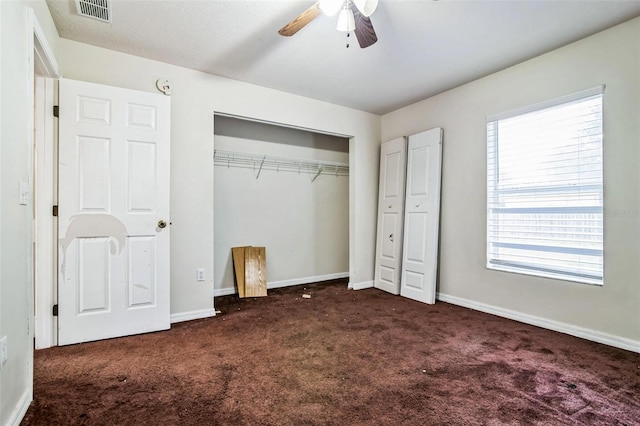 unfurnished bedroom featuring dark colored carpet, ceiling fan, and a closet