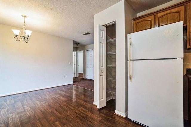 kitchen featuring a textured ceiling, an inviting chandelier, white fridge, dark hardwood / wood-style flooring, and pendant lighting