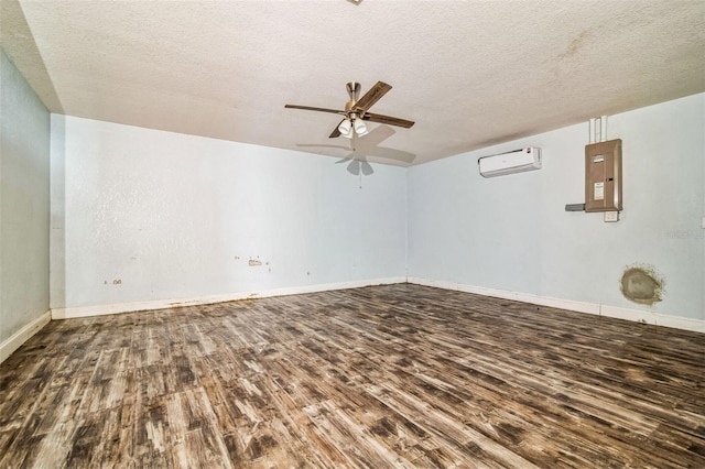 spare room featuring a wall mounted AC, electric panel, ceiling fan, hardwood / wood-style flooring, and a textured ceiling