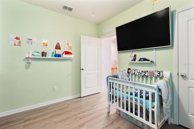 bedroom with hardwood / wood-style flooring and a crib