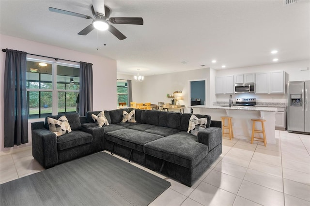 living room featuring ceiling fan with notable chandelier, sink, and light tile patterned floors