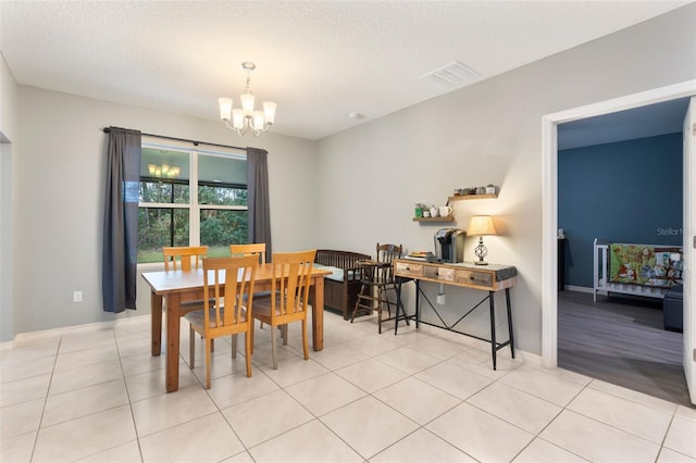 dining space featuring an inviting chandelier, a textured ceiling, and light tile patterned flooring