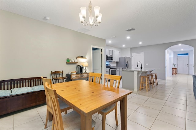 dining space with a textured ceiling, sink, a chandelier, and light tile patterned floors