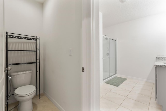 bathroom with toilet, a textured ceiling, walk in shower, tile patterned floors, and vanity