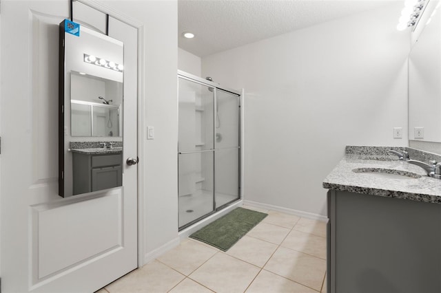 bathroom featuring vanity, tile patterned floors, a shower with door, and a textured ceiling