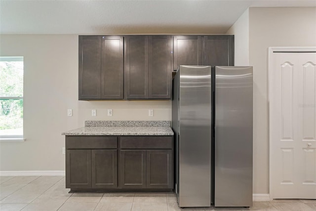 25122 Ensley Rd, Sorrento, FL 32776 - kitchen with freestanding refrigerator, dark brown cabinetry, light tile patterned flooring, and light stone counters