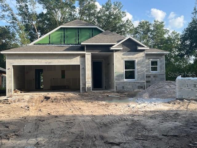 25122 Ensley Rd, Sorrento, FL 32776 - view of front facade with a garage, roof with shingles, driveway, and stone siding