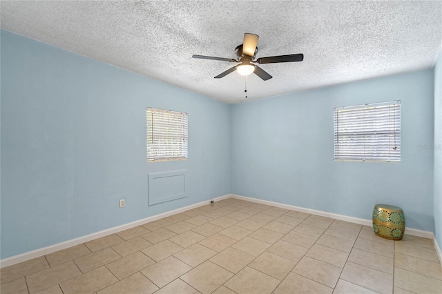 tiled empty room with ceiling fan, plenty of natural light, and a textured ceiling