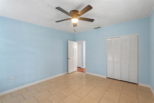 unfurnished bedroom featuring ceiling fan, light tile patterned floors, a closet, and a textured ceiling