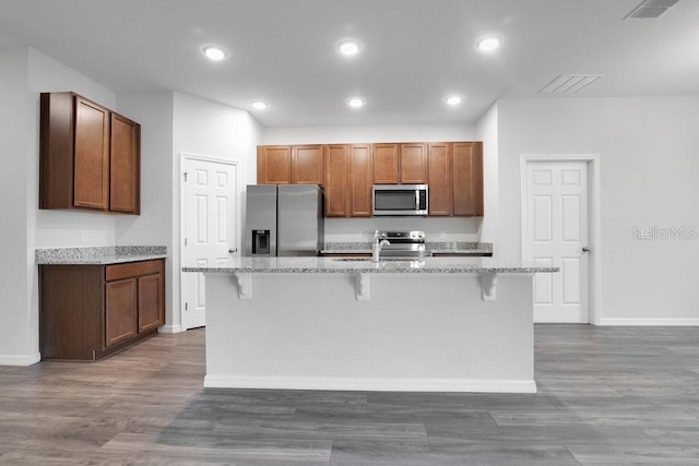 kitchen with stainless steel appliances, a kitchen bar, and a kitchen island with sink