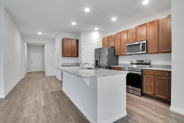 kitchen with a center island with sink, a breakfast bar area, stainless steel appliances, light stone countertops, and sink