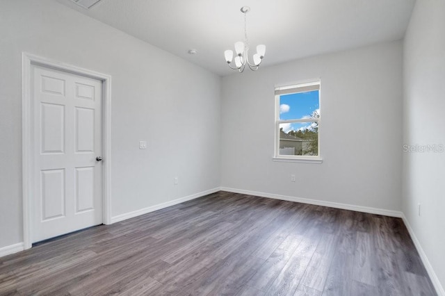 unfurnished room featuring dark hardwood / wood-style floors and a chandelier