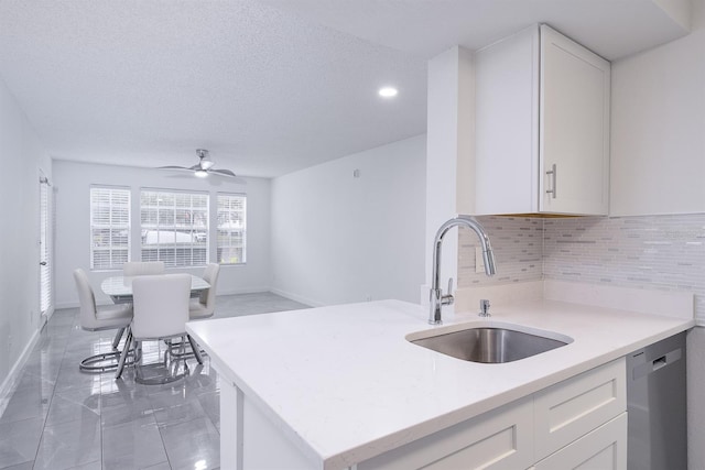 kitchen with ceiling fan, tasteful backsplash, stainless steel dishwasher, white cabinets, and sink