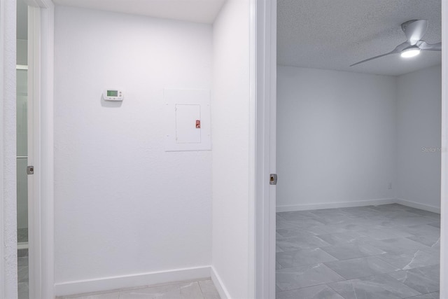 laundry area with a textured ceiling, ceiling fan, and electric panel