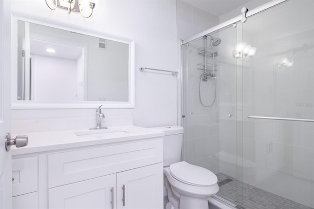 bathroom featuring toilet, vanity, and a shower with door