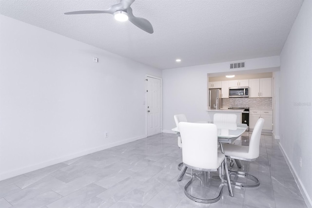 dining area featuring ceiling fan and a textured ceiling