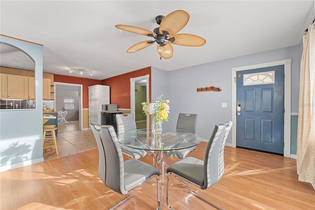 dining space with light wood finished floors, ceiling fan, and baseboards