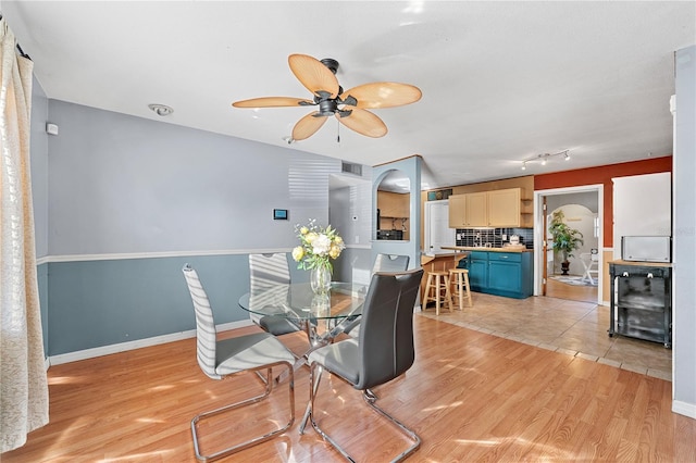 dining space with arched walkways, visible vents, light wood-style floors, beverage cooler, and baseboards