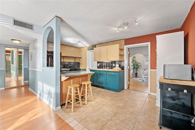 kitchen with open shelves, light countertops, visible vents, blue cabinets, and a kitchen bar