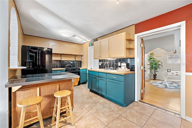 kitchen featuring stainless steel countertops, a breakfast bar, blue cabinetry, black appliances, and open shelves