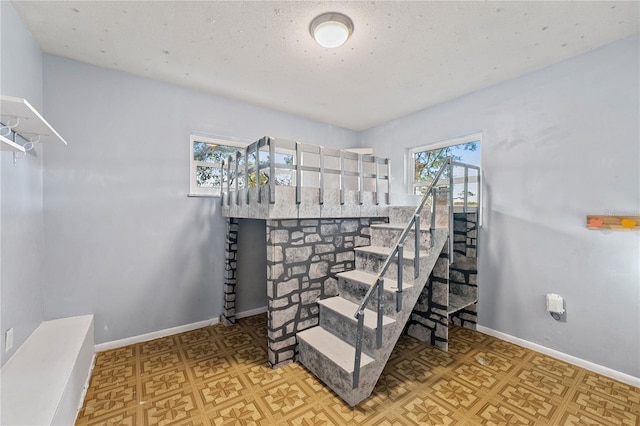 stairway featuring a textured ceiling, baseboards, and tile patterned floors