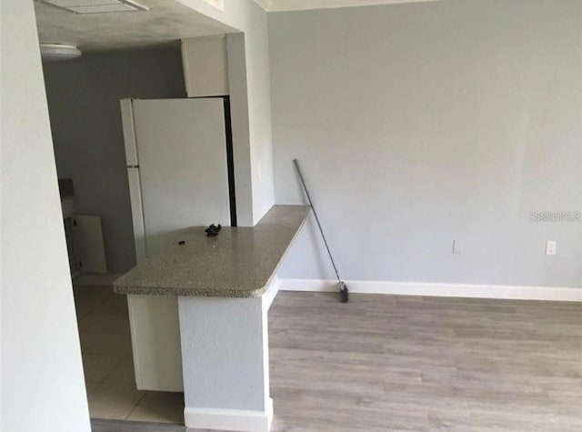 kitchen with white refrigerator, light hardwood / wood-style floors, and kitchen peninsula