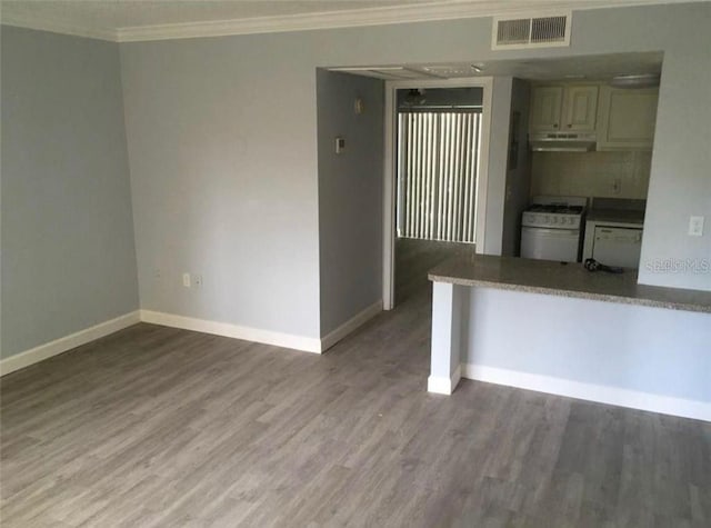 interior space with wood-type flooring, decorative backsplash, crown molding, and white gas range