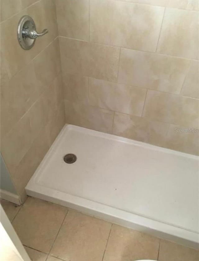 bathroom with a tile shower and tile patterned floors