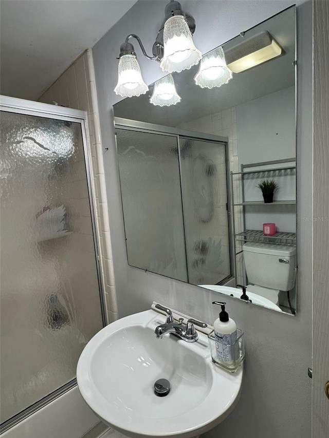 bathroom with sink, an enclosed shower, and toilet