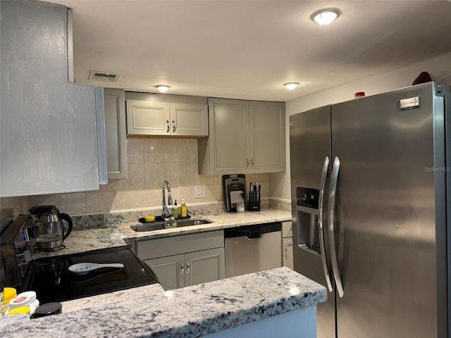 kitchen featuring appliances with stainless steel finishes, tasteful backsplash, sink, gray cabinets, and light stone counters