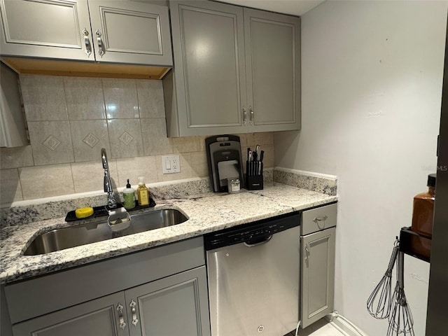 kitchen featuring stainless steel dishwasher, light stone countertops, sink, and gray cabinets