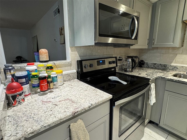 kitchen with appliances with stainless steel finishes, decorative backsplash, and gray cabinets