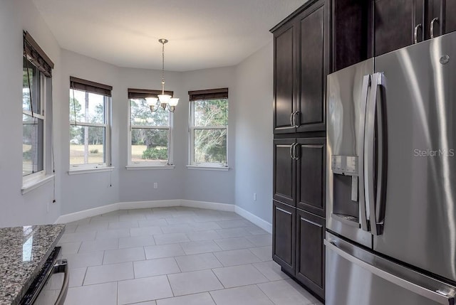 kitchen featuring stainless steel fridge with ice dispenser, an inviting chandelier, a wealth of natural light, and light stone counters