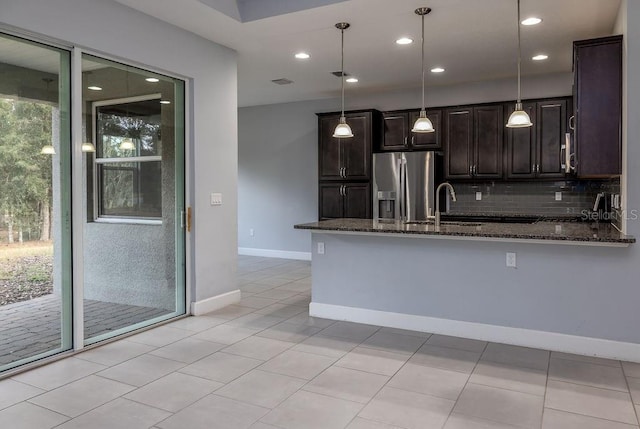 kitchen with pendant lighting, stainless steel refrigerator with ice dispenser, dark stone counters, decorative backsplash, and light tile patterned floors