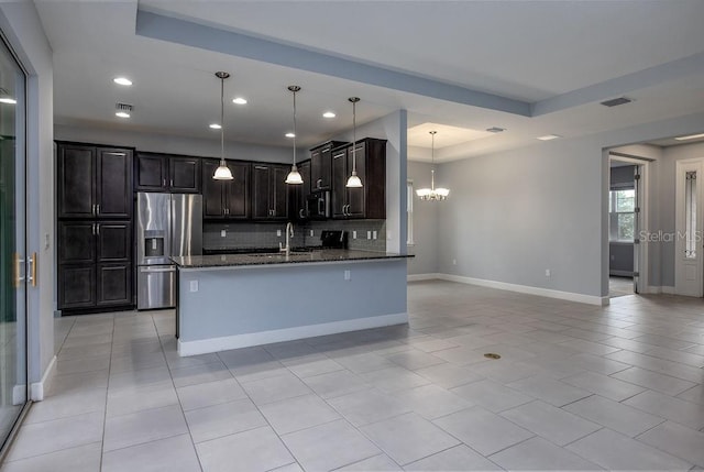 kitchen with pendant lighting, a raised ceiling, decorative backsplash, stainless steel appliances, and dark stone counters