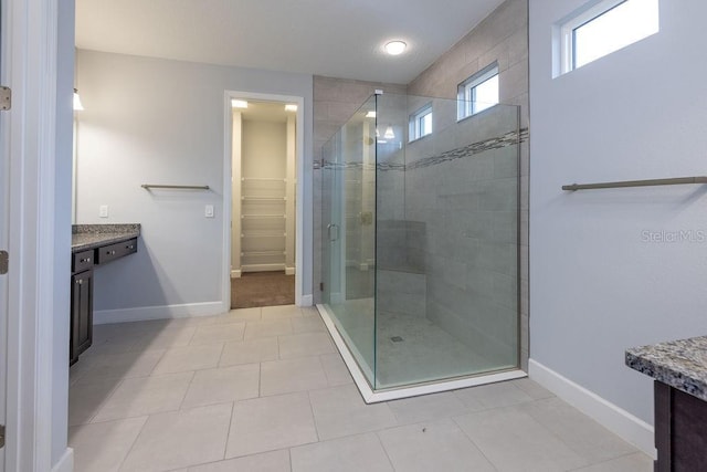 bathroom with walk in shower, vanity, and tile patterned floors