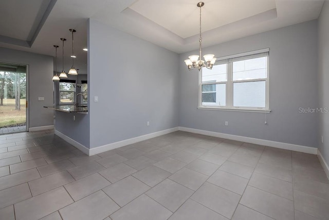 tiled spare room with a wealth of natural light, a chandelier, a raised ceiling, and sink