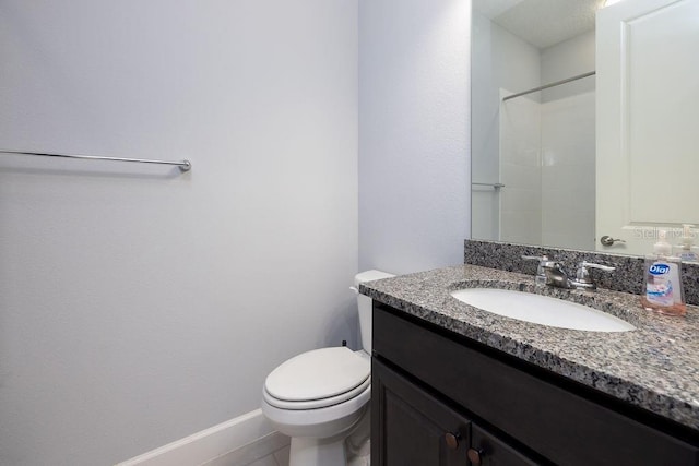 bathroom featuring toilet, vanity, and walk in shower