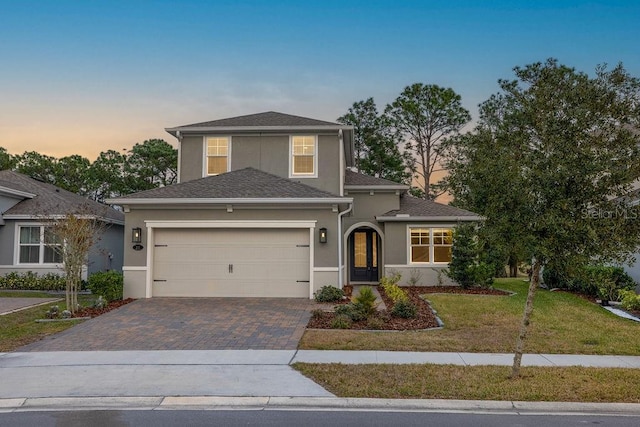 traditional-style house featuring an attached garage, a front lawn, stucco siding, and driveway