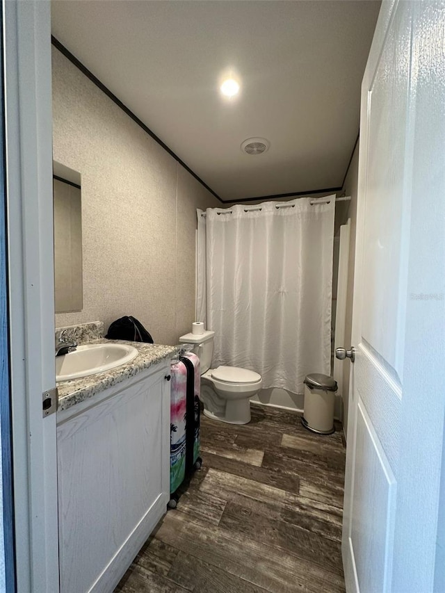 bathroom featuring hardwood / wood-style floors, toilet, vanity, and walk in shower