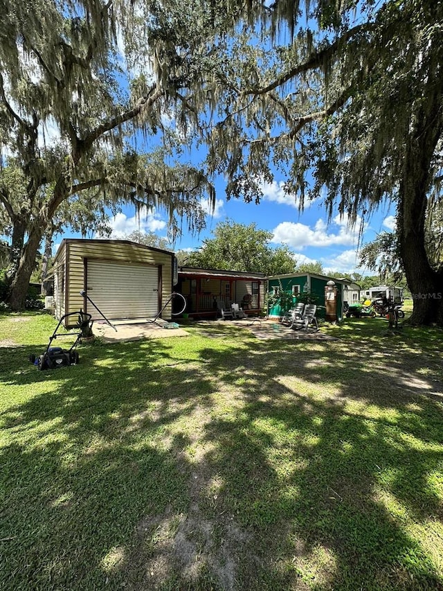 view of yard with a garage and an outbuilding