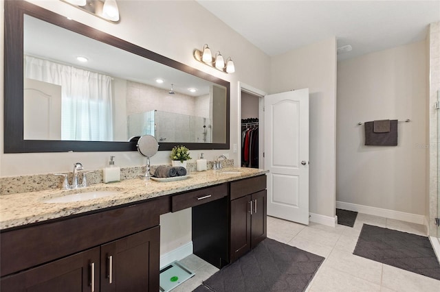 full bathroom featuring a stall shower, tile patterned flooring, a sink, and a walk in closet