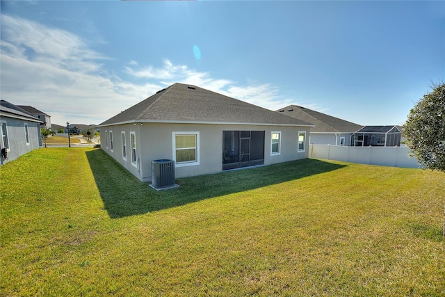 rear view of house with a shingled roof, fence, a yard, central AC, and stucco siding