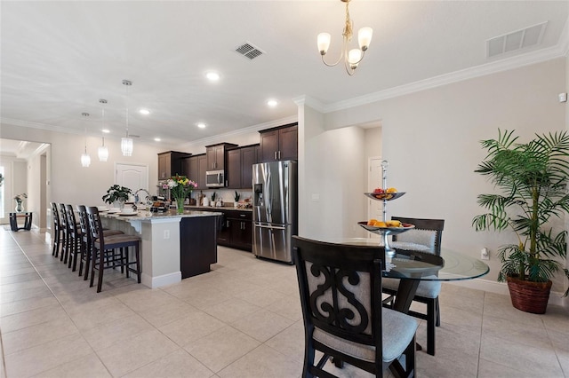 kitchen with stainless steel appliances, a center island with sink, visible vents, and dark brown cabinetry