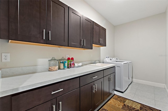 laundry room featuring cabinet space, light tile patterned floors, baseboards, washing machine and dryer, and a sink