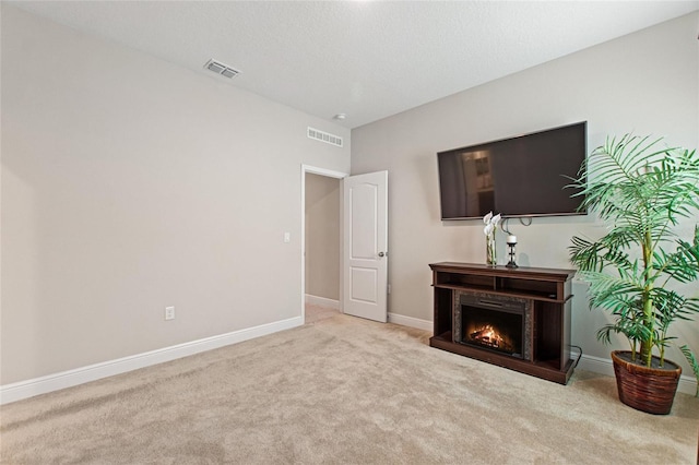 living area featuring a warm lit fireplace, carpet flooring, visible vents, and baseboards