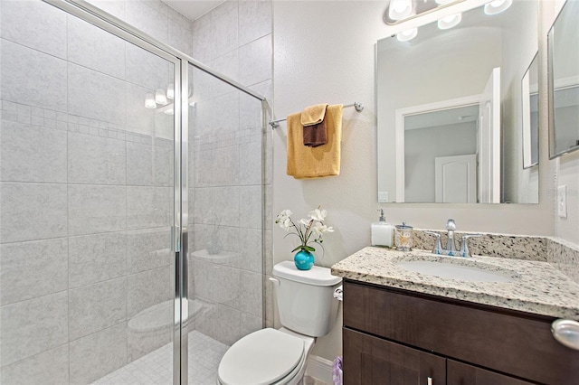 bathroom with a shower stall, toilet, and vanity